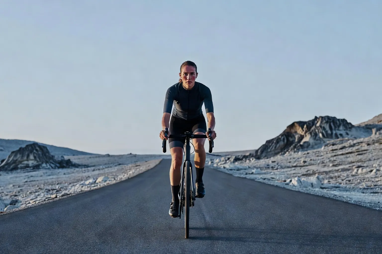 Cycliste vu de loin sur une route de montagne au petit matin, lumière froide